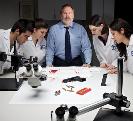 Keith Inman with four CSUEB students in white lab coats at at mock crime scene lab.